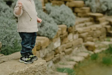 toddler alone outside holding a stick