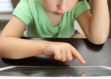 a toddler in a green shirt using a tablet
