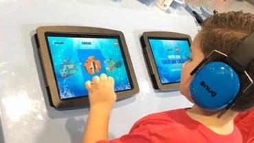 A child wearing headphones and using an iPad at LegoLand