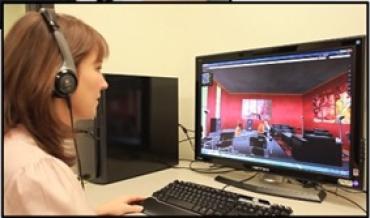 A woman wearing headphone on a computer play-based intervention