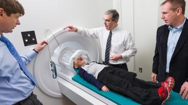 a woman getting an MRI with 3 doctors around her