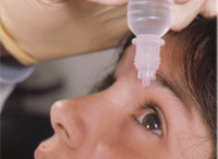 an adult helping a child use eye drops