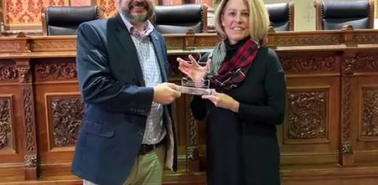 Autism Speaks staff Josh Cobbs handing puzzle piece shaped acrylic award to Rep. Meyer