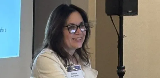 A woman in glasses standing at a podium to present