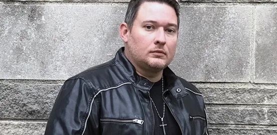 Ethan Cross wearing a leather jacket and cross necklace