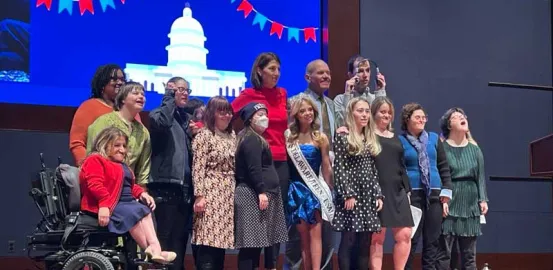 Group of 14 disability advocates standing together on stage