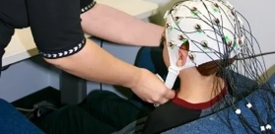 Katherine Stavropoulos placing an EEG cap on a boy