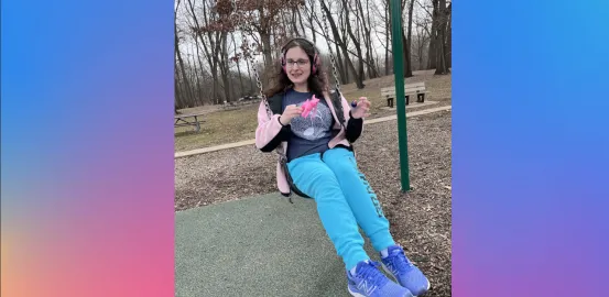 A young women with headphones on swingings on a swing set 