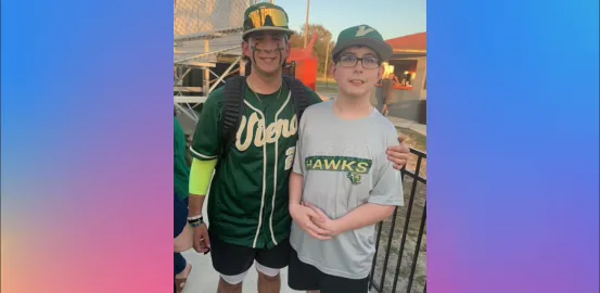 Two brothers stand side by side in green basebeball uniforms 