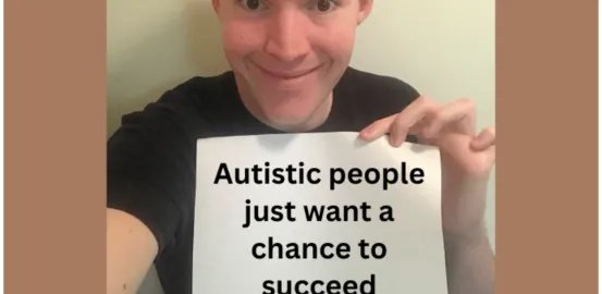 A man looks at the camera and holds a sign that says "Autistic people just want a chance to succeed" 