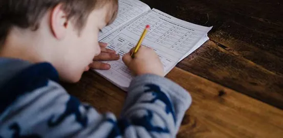 a child doing homework on a wooden table