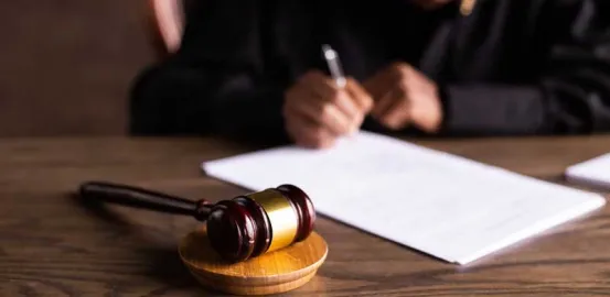 judge signing a document with wooden gavel resting nearby