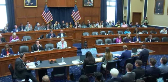 view of members of Congress seated in three rows in US Congressional hearing room