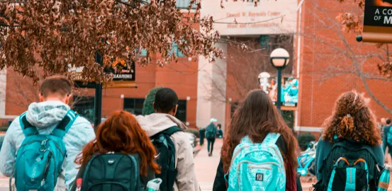 group of students wearing backpacks walking into school