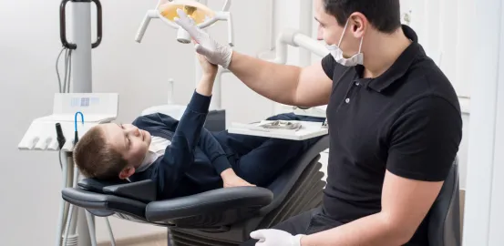 male dentist high fiving boy laying down in dental exam chair