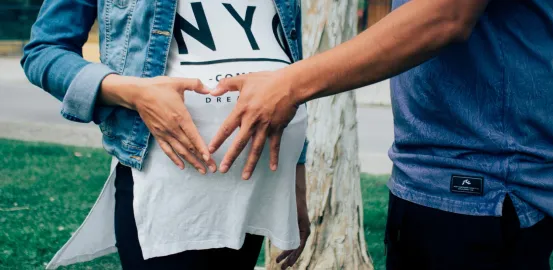 someone touching a pregnant woman's baby bump