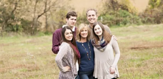 Kristi Jacobsen and her family posing for a photo outside in a pasture