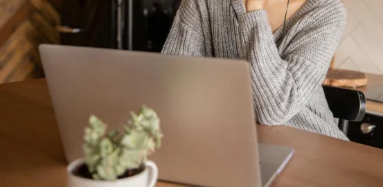 woman in a knit sweater looking at a laptop