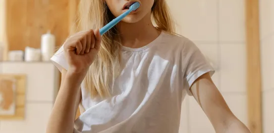 young girl with blonde hair brushing her teeth