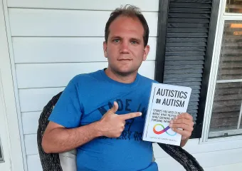 Josh holding a copy of the book "Autistics on Autism"