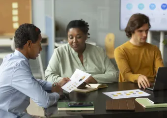 three people sitting at black table in the workplace