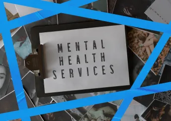 clipboard holding white paper with "MENTAL HEALTH SERVICES" written on it, laying on top of photos of people; five strips of blue tape surrounding sign