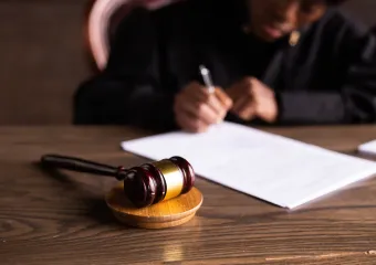 judge signing a document with wooden gavel resting nearby