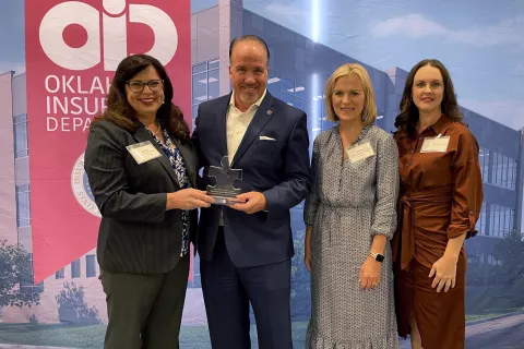 Christa Stevens handing Commissioner Mulready an puzzle shaped award with Judith Ursitti and Tara Hood standing next to them