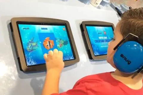 A child wearing headphones and using an iPad at LegoLand