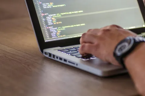 A mans hand typing code on a computer screen