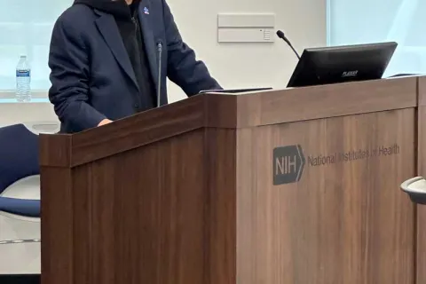 Andy Shih standing and presenting behind wooden podium