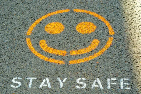 Smiley face and the words stay safe painted on a sidewalk