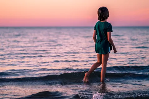 Child wandering alone by the ocean