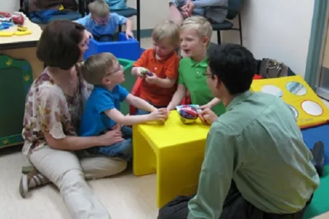 Dr. Lonnie Zwaigenbaum sitting on the floor with children