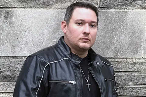 Ethan Cross wearing a leather jacket and cross necklace