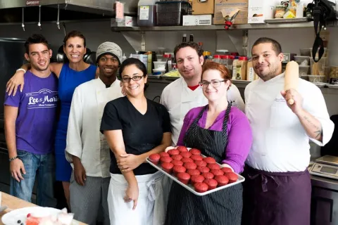 A group of adults working in a kitchen pose together