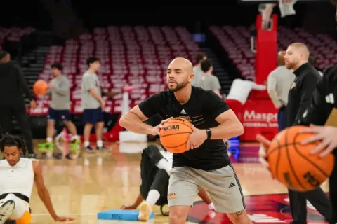 Man in black athletic shirt holding basketball on court