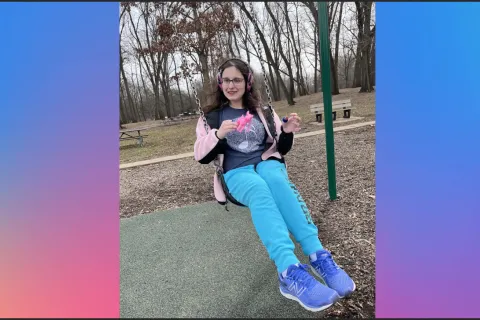 A young women with headphones on swingings on a swing set 