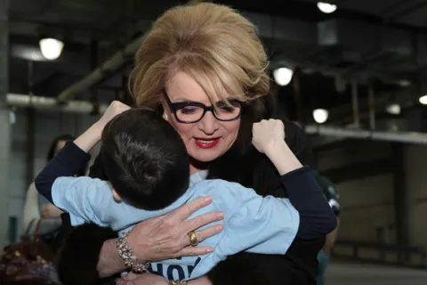 Suzanne Wright hugging a boy in a blue shirt