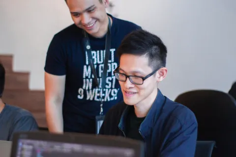 a man wearing glasses and a black shirt typing on a computer