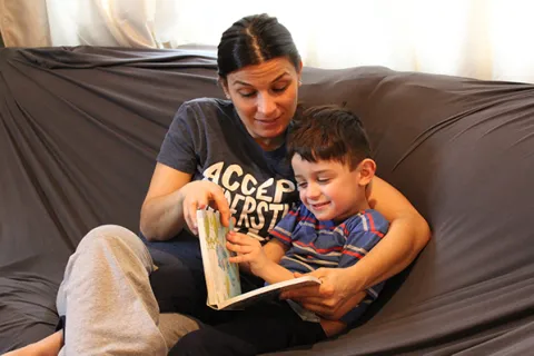 a mother reading her son a book on the couch