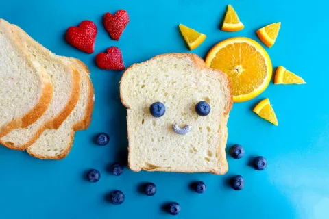 a piece of bread with fruit on top to make a smiley face