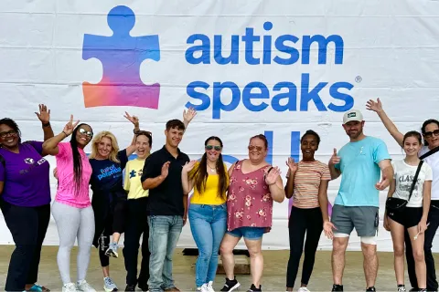 Group of people excited on stage at a local Walk standing in front of Autism Speaks banner