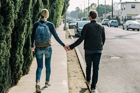 2 adults walking down the street holding hands