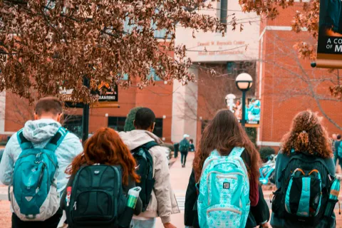 group of students wearing backpacks walking into school