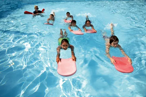 Young swimmers kicking in a pool with kickboards