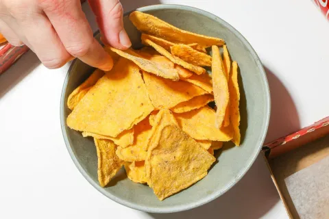 person with their hand in a bowl of chips
