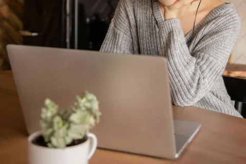 woman in a knit sweater looking at a laptop
