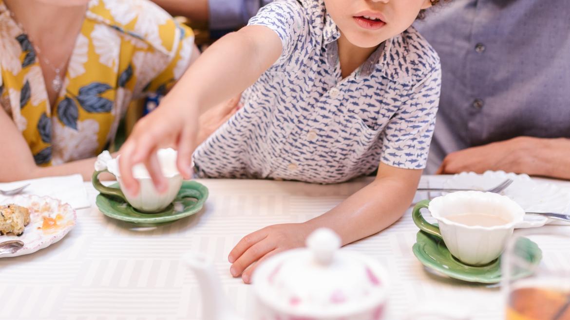 toddler reaching over the table while family is out to eat at a restaurant