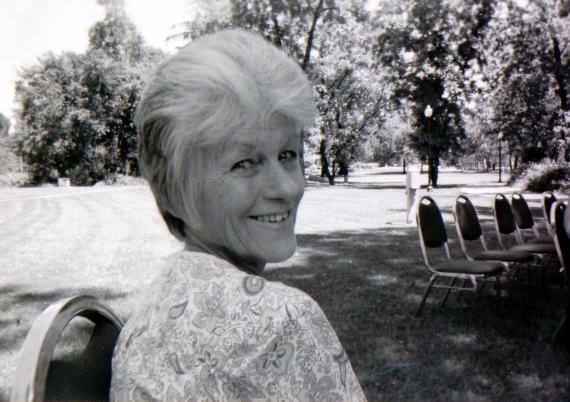 A women with short hair, sitting in a black chain on a lawn 
